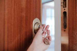 unrecognizable woman opening door home with keys and keyring with house shape.Home and lifestyle
